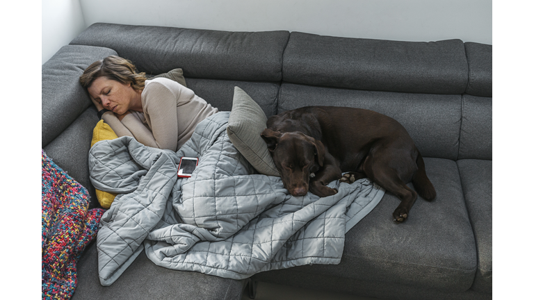 Woman asleep on sofa with pet dog
