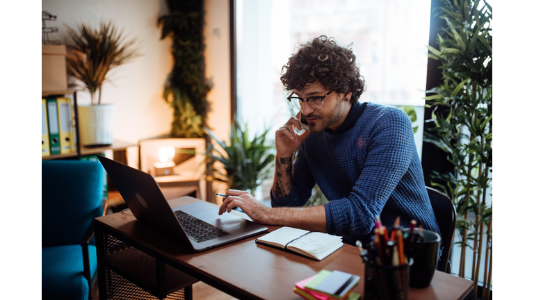 Young man talking on the phone in his home office