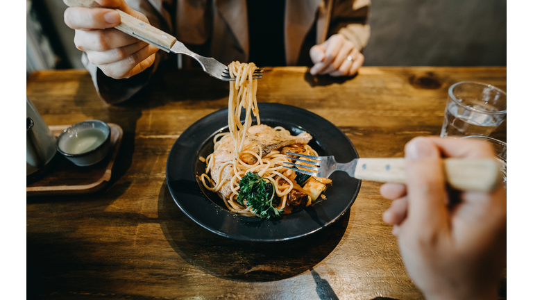 Hands of couple sharing and enjoying freshly made pasta in a restaurant