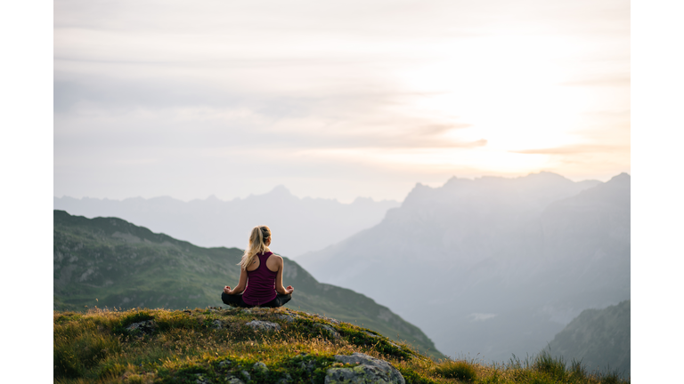 Woman performs yoga moves on mountain summit