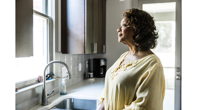 Senior woman looking out kitchen window