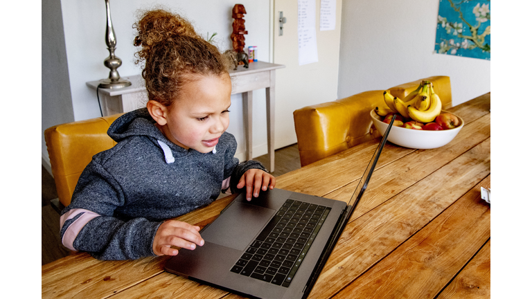 A child studies at home with a laptop as all the schools in