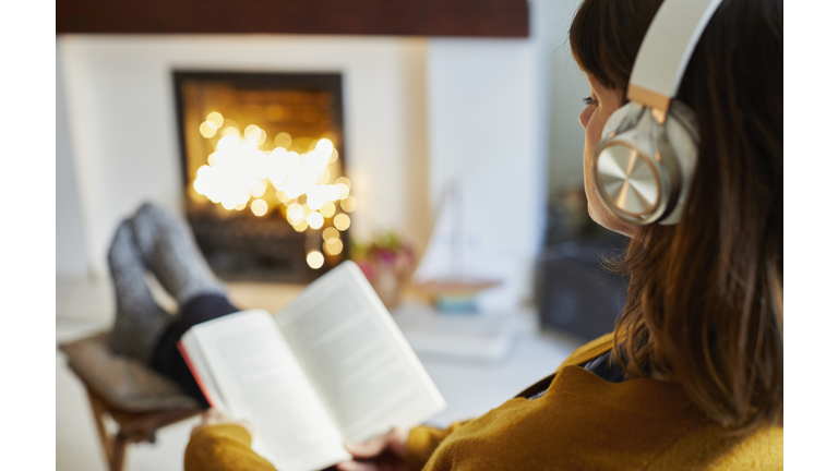 Woman with headphones reading in living room