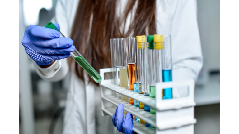 Female Scientist showing multi colored test tubes examples