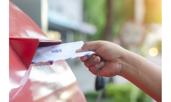 posting a letter to red british postbox on street