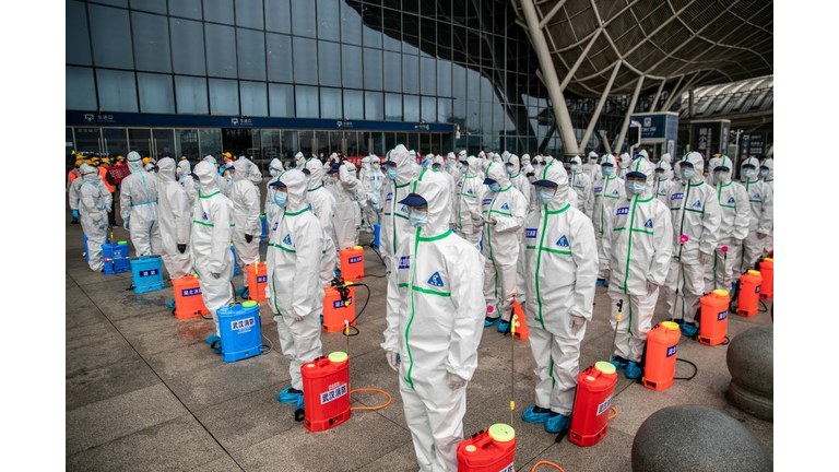 Staff members line up at attention as they prepare to spray disinfectant at Wuhan Railway Station in Wuhan in China's central Hubei province on March 24, 2020. 