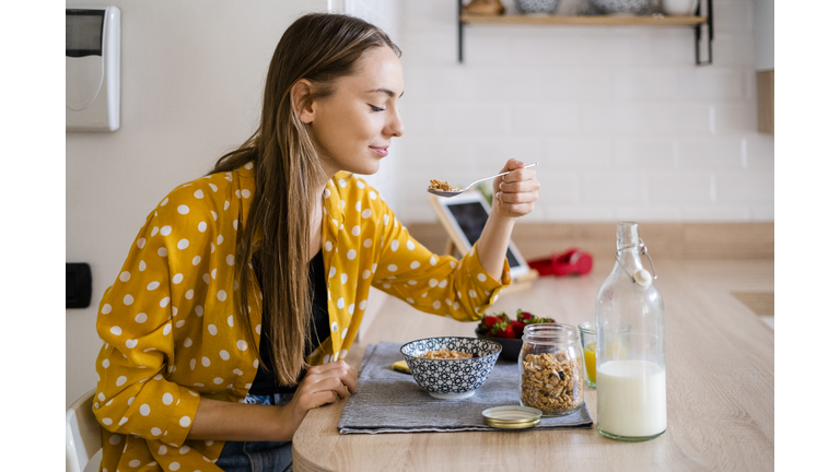 Young woman enjoying breakfast in kitchen at home