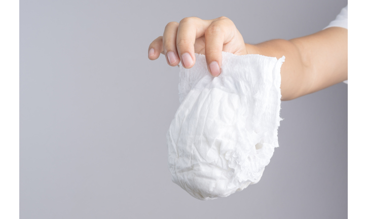 Cropped Hand Of Person Holding Diaper Against Gray Background
