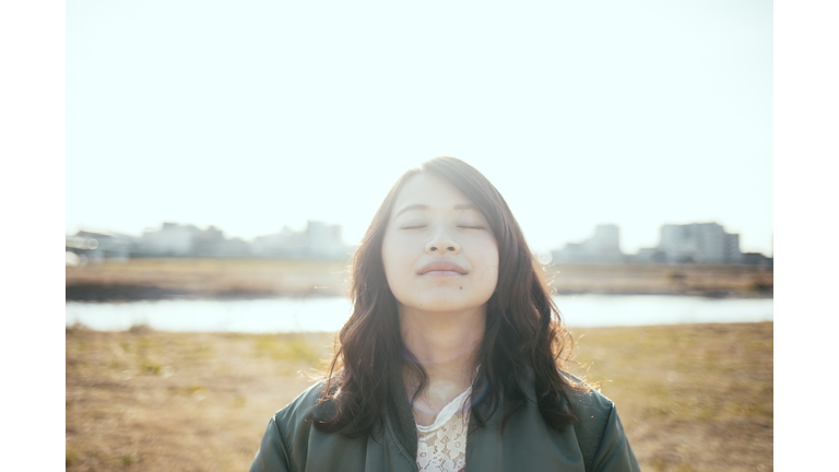 Girl closing her eyes at the river bank