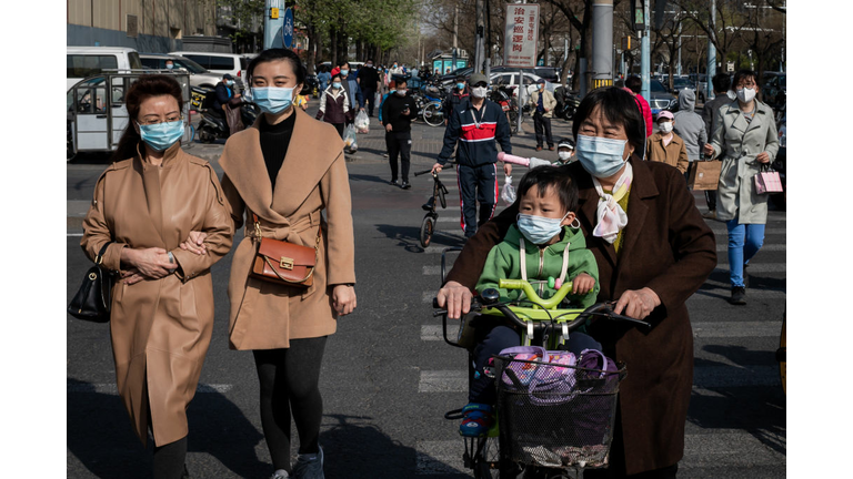 People wearing face masks amid the COVID-19 coronavirus pandemic cross a street in Beijing.