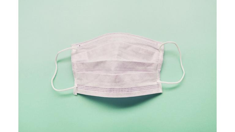 High angle view of a white face mask on green background