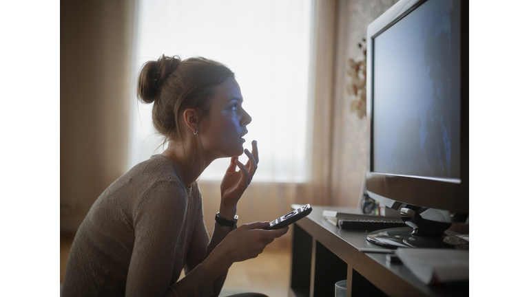 young woman looking in suspense at tv