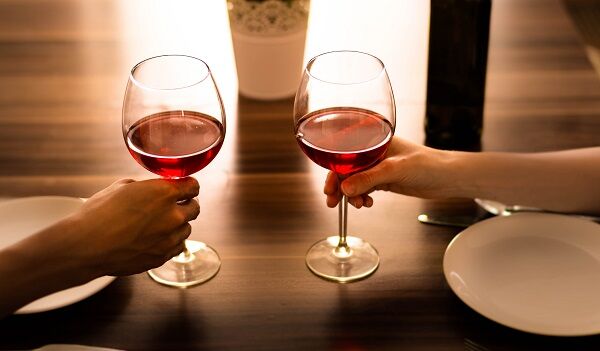 Romantic dinner. Two people each holding a glass of wine.