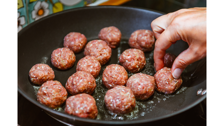 Cropped Image Of Hand Frying Meatballs In Pan