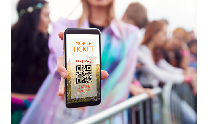 Close Up Of Woman Holding Mobile Phone Screen To Camera As She Arrives At Entrance To Music Festival