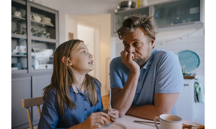 Daughter talking to father in kitchen at home