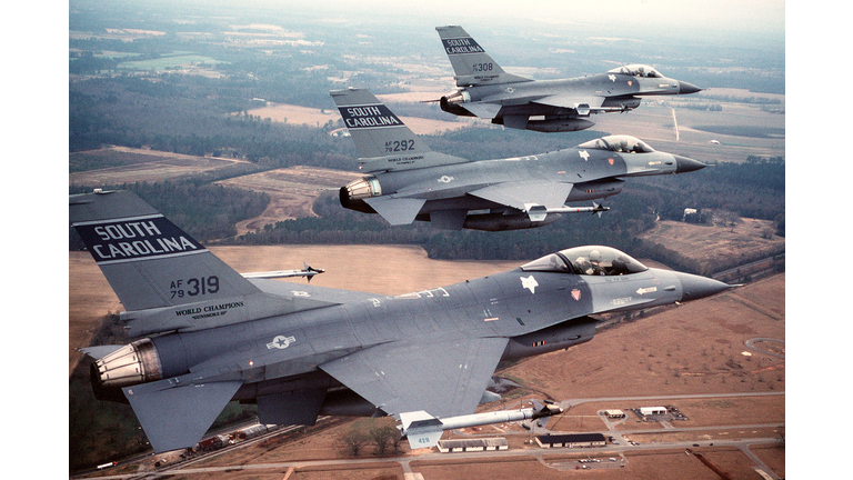 An air-to-air right side view of three F-16 Fighting Falcon aircraft