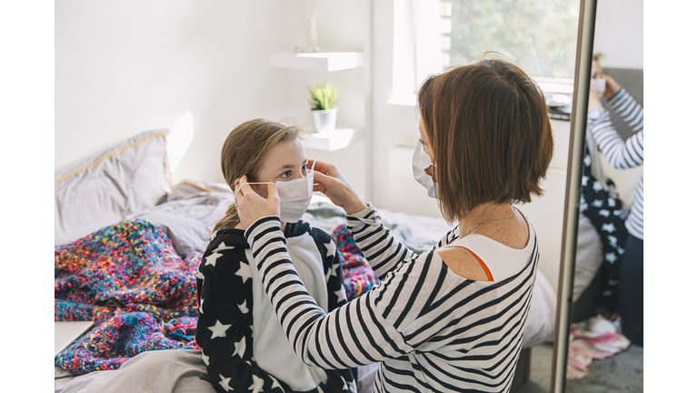 Mother putting mask on daughter