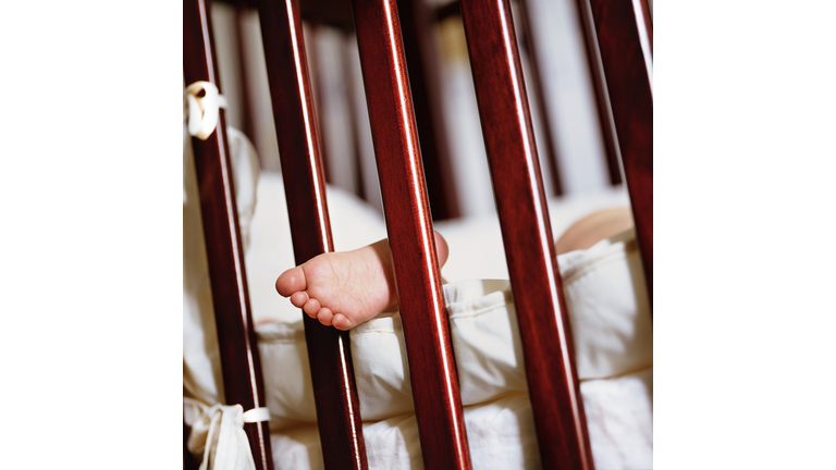 A child's foot sticking through the bars of a cot