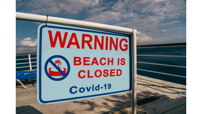 Beach is closed due to Covid-19 warning sign located at an entrance to a beach. Social media campaign for coronavirus prevention. Summer is cancelled, shutdown concept