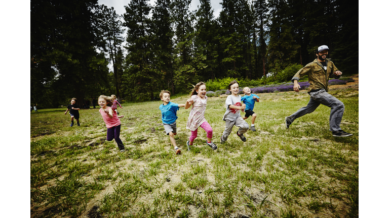 Camp counselor playing tag with young kids