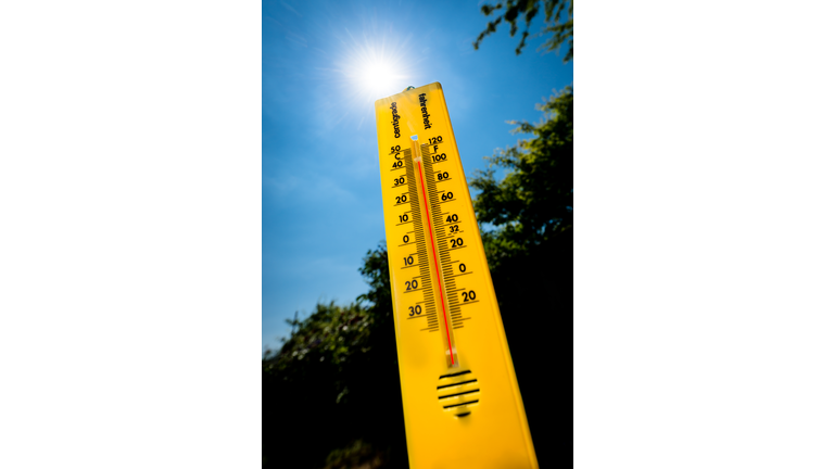 A Yellow Thermometer Against a Bright Sunlit Sky