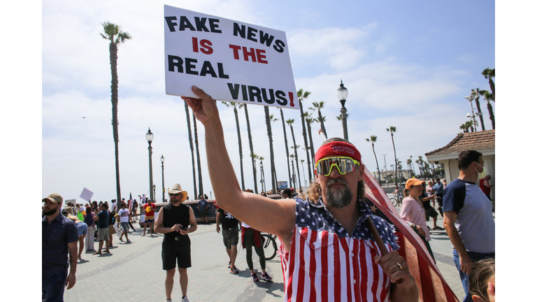 A protester holds a placard that says Fake News Is The Real