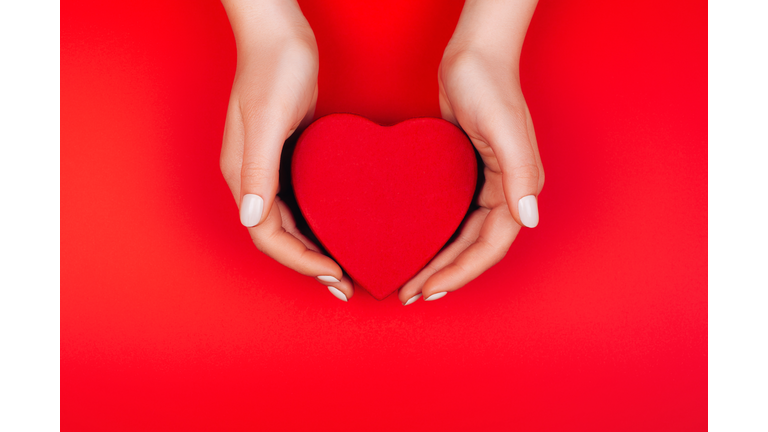 Red heart gift box in woman hands