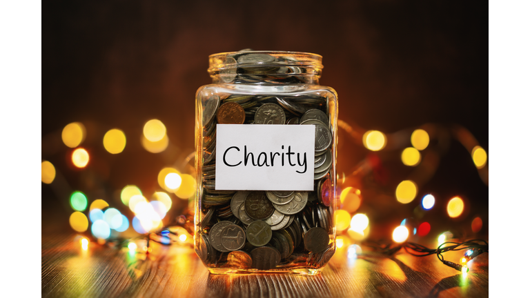 Jar of Coins for Charity Against Christmas Lights Background
