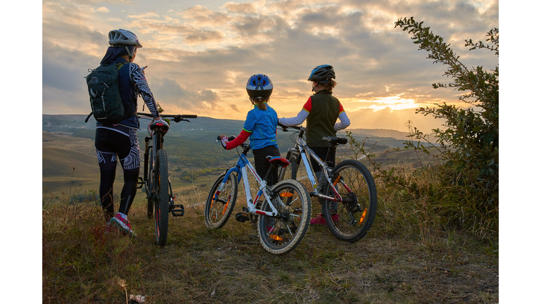 Happy mountain bike family,  outdoors have fun together on a summer afternoon sunset, cycling girls activity