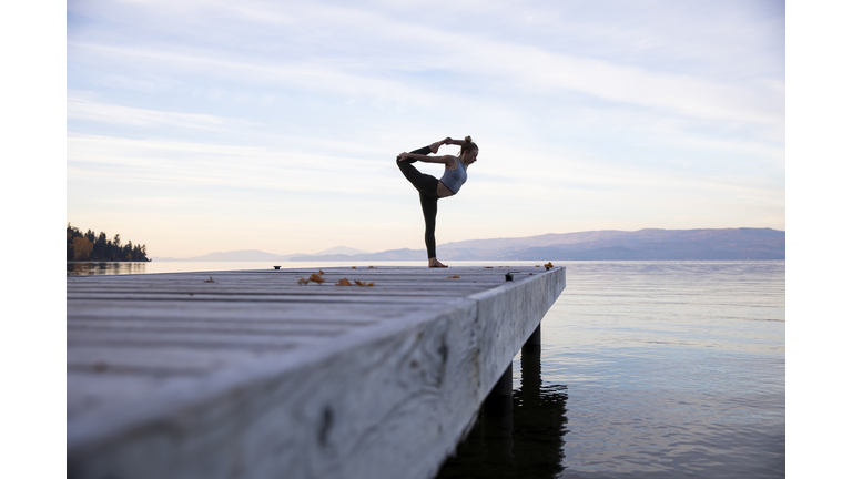A woman doing yoga on a dock
