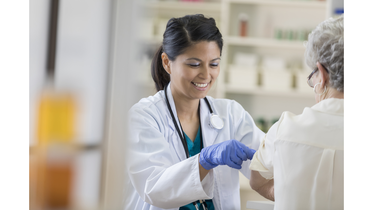 Young pharmacist places a band-aid on customer's arm after flu shot
