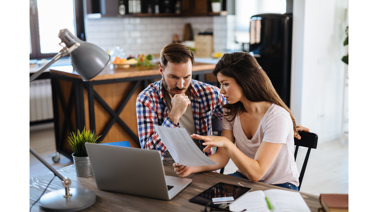 Frustrated couple checking bills at home using laptop