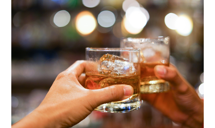 two men clinking glasses of whiskey drink alcohol beverage together at counter in the pub