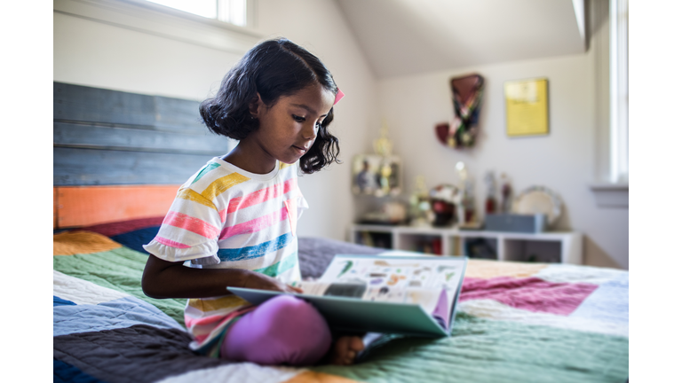 Girl reading book on her bed