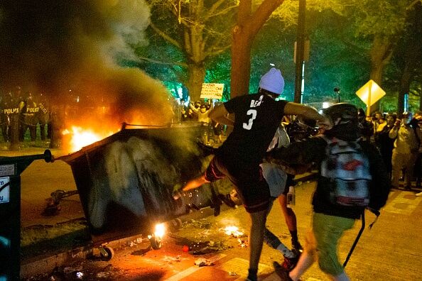 Demonstrator kicks a burning dumpster outside of the White House on May 30, 2020 in Washington D.C.