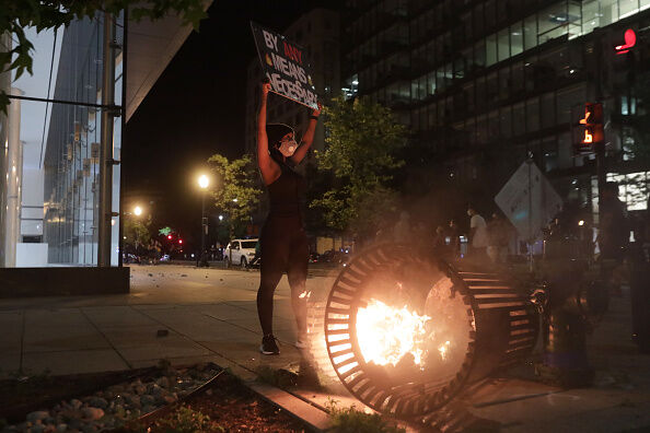 A demonstrator stands near a trash can fire near the White House while protesting the killing of George Floyd in the early morning hours on May 31, 2020 in Washington, DC.