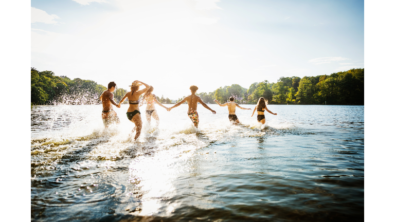 Friends Wading Into Lake In Summer Sun