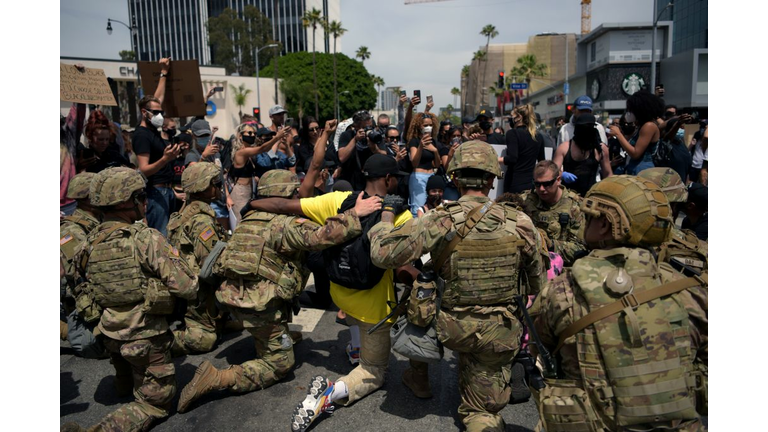 Protesters and members of the Army National Guard kneel together
