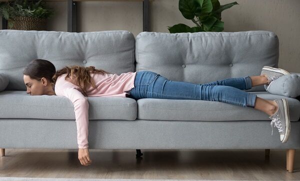 Young woman lying buried her face in sofa feels tired