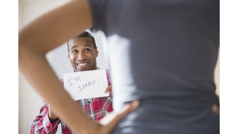 Man showing 'I'm Sorry' sign to angry girlfriend