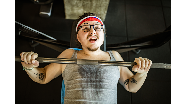 Above view of funny athlete exercising on a bench press in a gym.