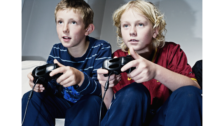 Boys playing with games consoles