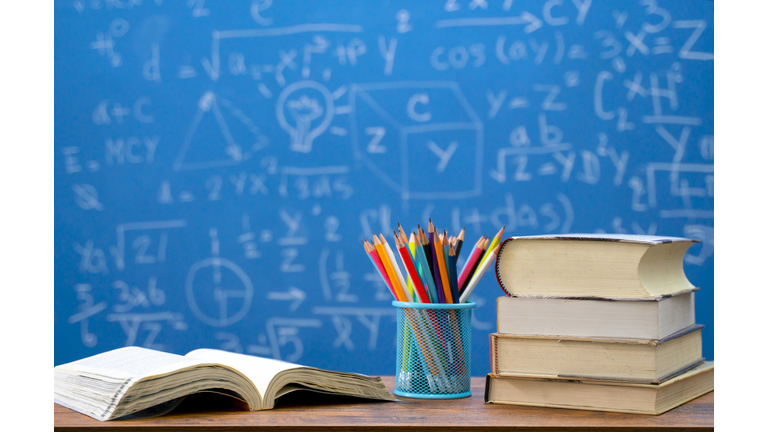 Back to school supplies. Books and blackboard on wooden background