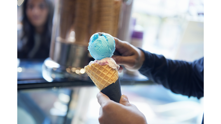 Man scooping ice cream onto cone