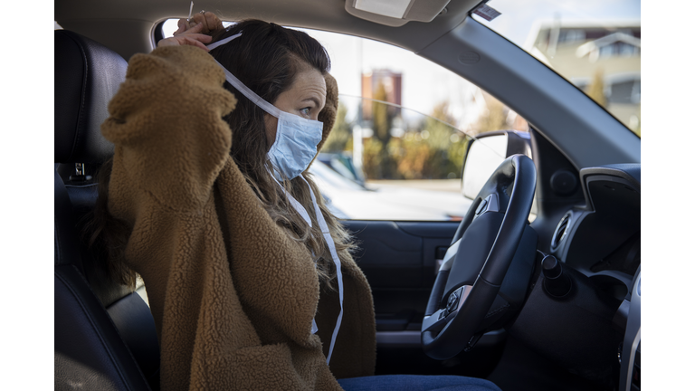 A woman driving her vehicle wearing latex gloves and a mask during the COVID-19 pandemic.