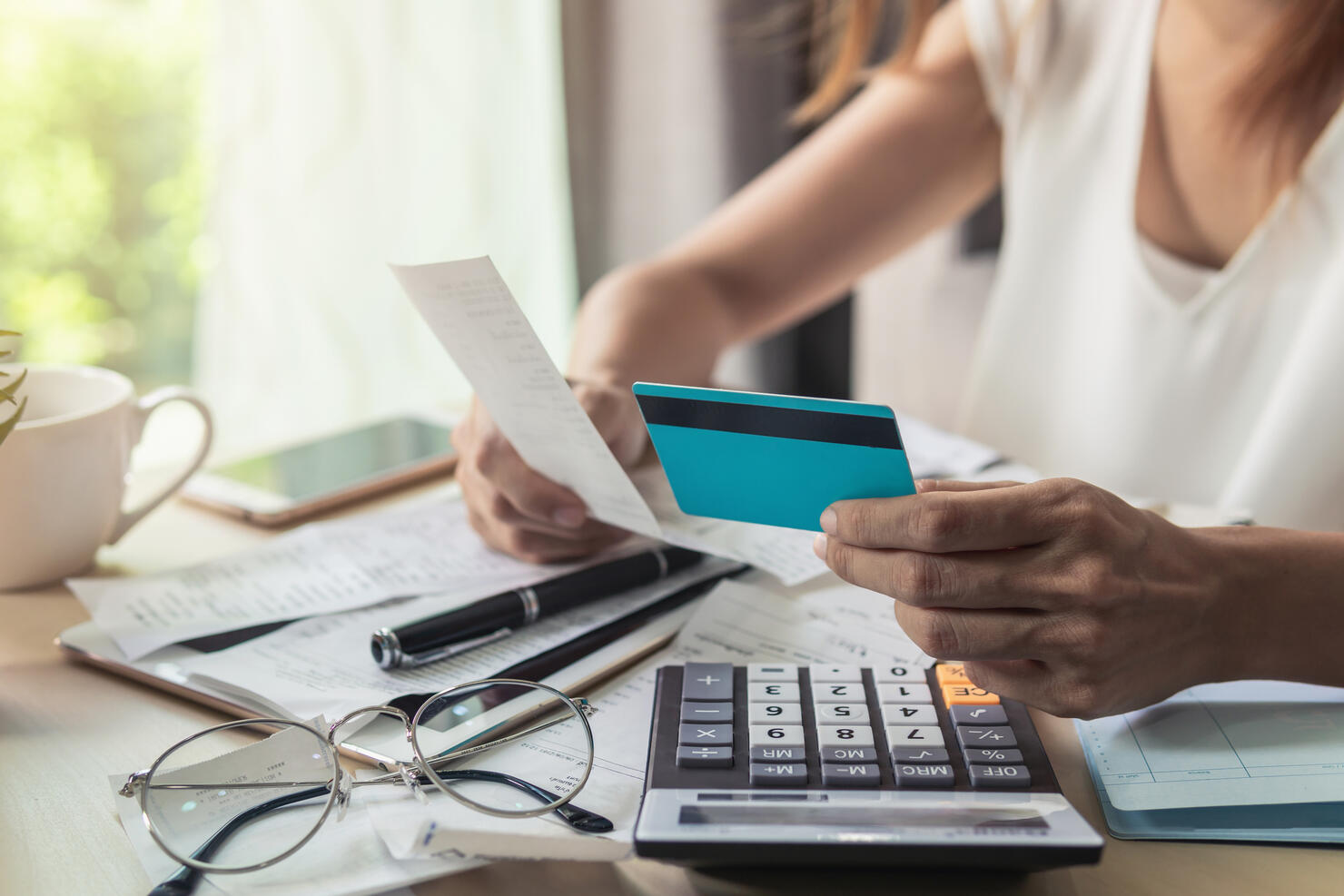 Midsection Of Businesswoman Holding Credit Card And Bill While Working At Desk