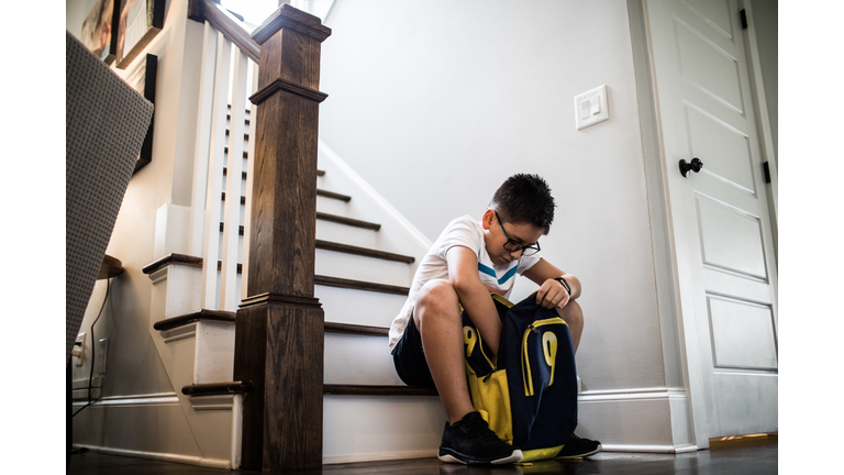 School age boy looking through backpack