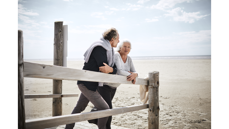 Senior couple standing on boardwalk on the beach