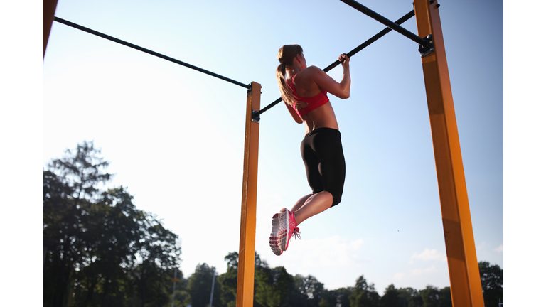 Girl training on chin-up bar outdoor